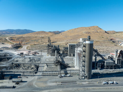 Aerial view of the Lehigh Cement Plant featuring industrial silos, conveyor belts, and processing structures set against arid hills in Tehachapi, California, United States.