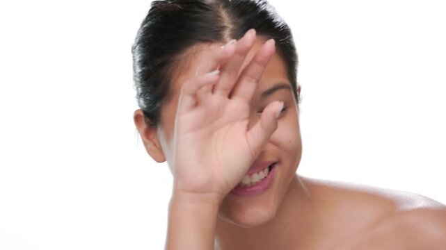 Closeup shot of young woman covering one eye with dorsal hand and laughing showcasing clear skin on white bg | Cleansing milk beauty commercial concept