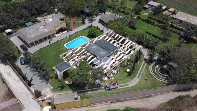 Aerial view of a wedding venue with a decorated marquee, swimming pool, and lush gardens in Lima, Callao Region, Peru.
