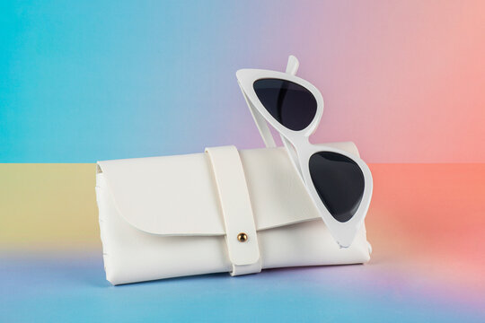 Sunglasses, fashion eyewear, and a glasses case against a colorful background.
