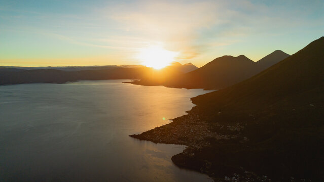 Aerial view of Rostro Maya overlooking Lake Atitlan at sunrise, with the town of Santa Clara la Laguna nestled along the shoreline in Santa Clara la Laguna, Solola, Guatemala.