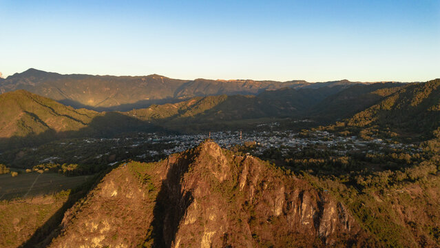 Aerial view of Rostro Maya peak with the town of Santa Clara la Laguna nestled in the mountainous landscape under golden hour light in Santa Clara la Laguna, Solola, Guatemala.