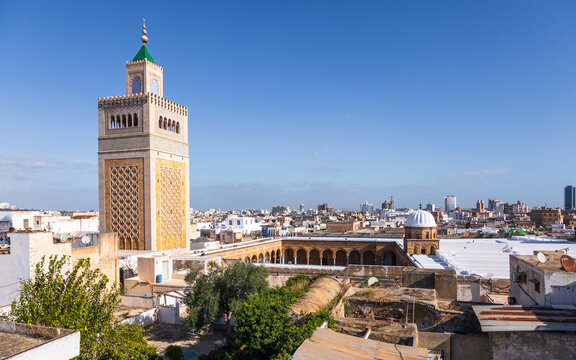 View of Al-Zaytuna Mosque with its distinctive minaret and courtyard, overlooking the historic rooftops of the medina under a clear blue sky, Tunis, Tunis Governorate, Tunisia.