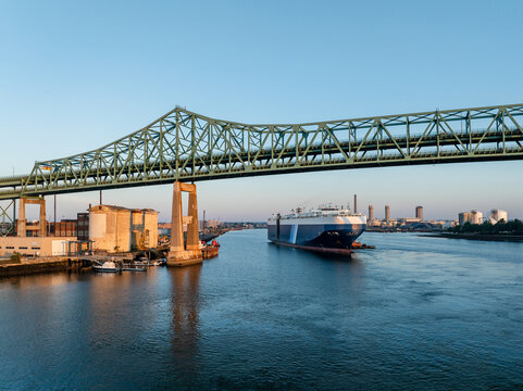 Aerial view of a large vehicle carrier ship passing under the Tobin Bridge on the Mystic River in Boston, Massachusetts, United States.