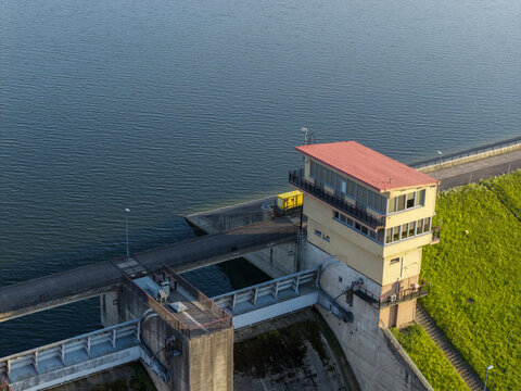 Aerial view of Lake Dobczyce dam featuring a control tower with a red roof, concrete infrastructure, and green embankments in Myslenice County, Lesser Poland Voivode, Poland.