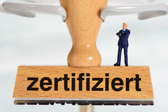 Ein Gesch&auml;ftsmann als Modellfigur steht auf einem Holzstempel mit dem Aufdruck: zertifiziert
