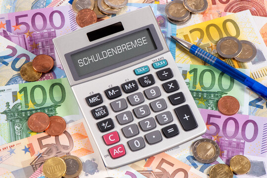 Auf vielen Euroscheinen liegt ein Taschenrechner mit dem Wort Schuldenbremse im Display - FOTOMONTAGE