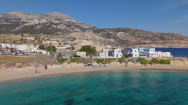 Drone footage capturing Lefkos Beach in Karpathos, revealing crystal-clear turquoise waters before unveiling a second stunning beach with equally vibrant waters beyond.