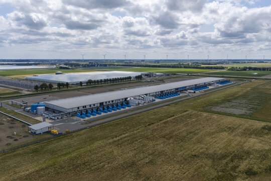 Aerial view of the Google data center facility surrounded by green fields and wind turbines in the Netherlands.