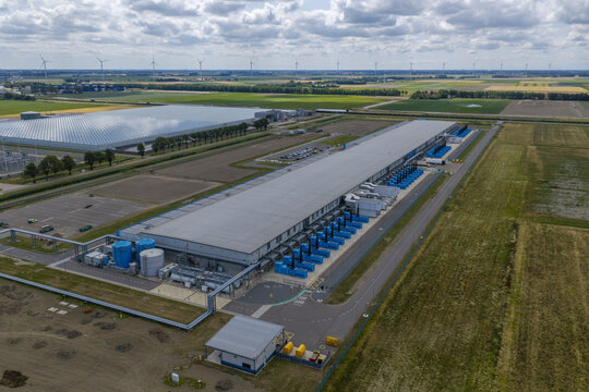 Aerial view of the Google data center facility featuring large industrial buildings, cooling infrastructure, and surrounding agricultural fields, Netherlands.