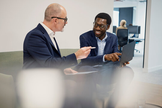 Businessmen discuss a project on a laptop in a London office