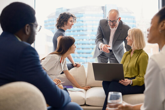 A business team discusses work around a laptop in a London office