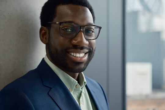 Smiling businessman in a suit stands confidently in a London office