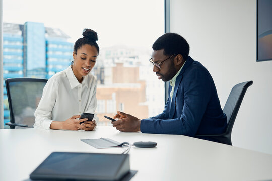 Businessman and businesswoman use smartphones in a London office