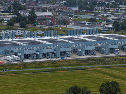 Aerial view of the Google data center facility with industrial buildings, cooling infrastructure, and solar panels, located near green fields and industrial zones in Winschoten, Netherlands.