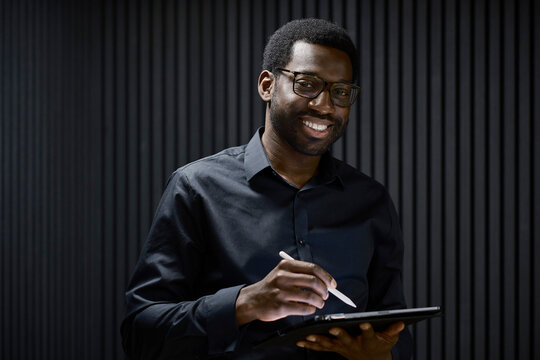 Smiling businessman holding tablet computer in London office