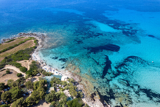 Aerial view of Plage de Ghjunchitu featuring turquoise waters, rocky coastline, and Mediterranean vegetation in Corbara, Corse, France.