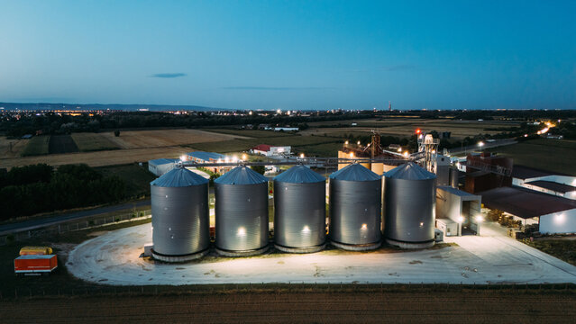 Aerial view of grain silos illuminated at night in the rural landscape of Sremska Mitrovica, Vojvodina, Serbia.