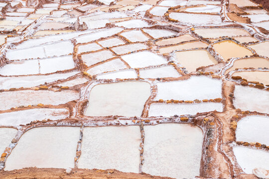 View of the historic salt evaporation ponds at Maras with terraced pools filled with salt and water in Cusco, Cusco, Peru.