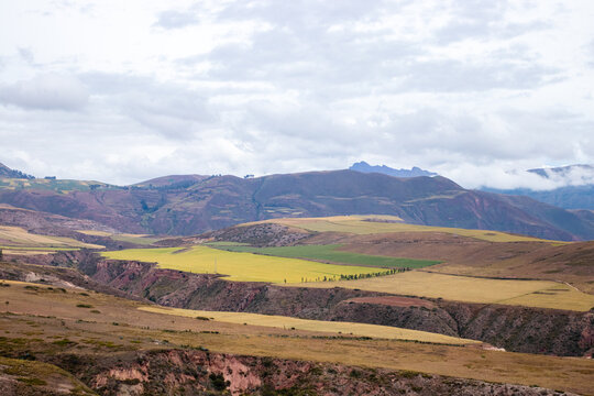 View of rolling agricultural fields and mountains in the Andean highlands near Cusco, Cusco, Peru.
