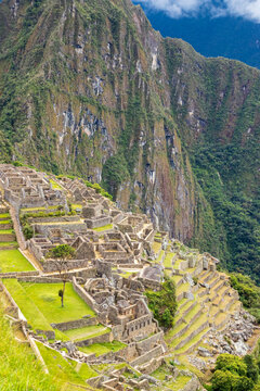 View of the historic Inca citadel of Machu Picchu with stone ruins, terraced fields, and steep mountain peaks in the background in Cusco, Cusco, Peru.
