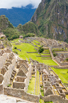 View of the historic Inca citadel of Machu Picchu featuring ancient stone ruins and green agricultural terraces set against dramatic mountain peaks in Cusco, Cusco, Peru.