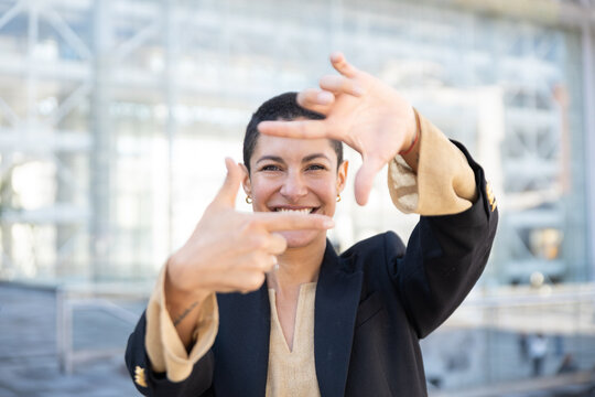 Smiling businesswoman makes a finger frame outside an office plaza