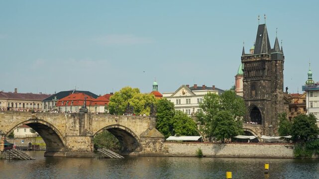 Charles Bridge and Old Town Bridge Tower stand across the Vltava River in Prague. Famous Czech landmark showcases historic European architecture for vacation travel and city sightseeing.