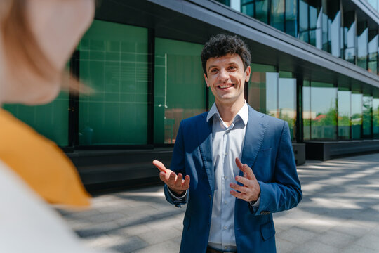 A smiling businessman talks to a businesswoman outside the office