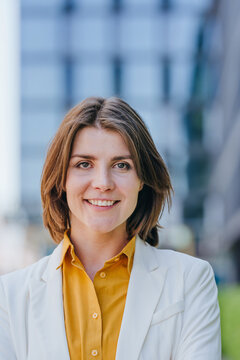 Smiling businesswoman stands outdoors in formal wear