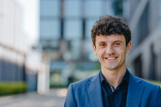 A smiling businessman wears formal wear outdoors in the city