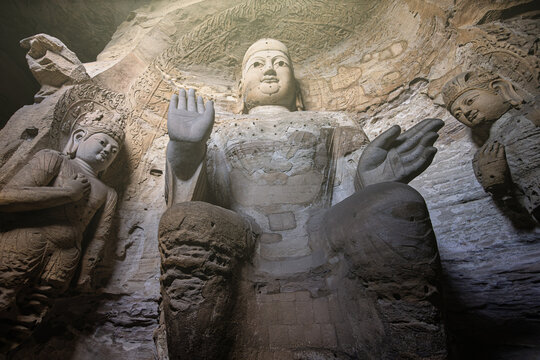View of the monumental Buddha statue carved into the rock face at the historic Yungang Grottoes in Datong, Shanxi, China.
