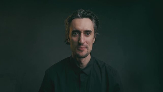 smile blink will be surprised Middle-aged man with neutral expression seated against a dark textured background in a minimalist studio portrait for business and personal branding