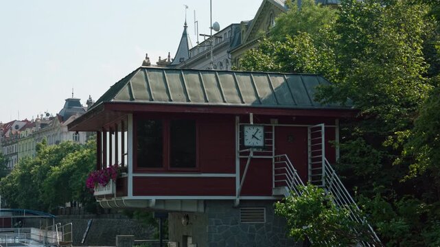 Smichov canal lock control house stands on Vltava River bank in Prague. Historic operator cabin regulates boat navigation. Iconic building shows European river transport infrastructure.