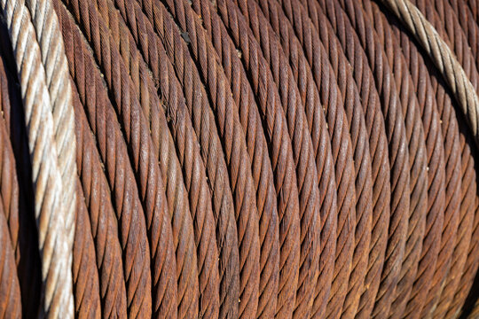 rusty steel wire rope with twisted metal strands, showing corrosion, weathered texture and industrial detail for engineering, construction, heavy equipment and maintenance concepts.