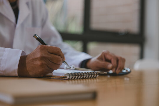 Doctor writing medical notes at a desk with stethoscope in clinic, representing healthcare documentation, patient records, diagnosis, prescription, medical consultation and professional care.