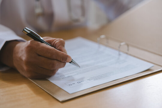 Doctor reviewing medical notes and patient records at a desk with stethoscope, representing healthcare documentation, clinical assessment, diagnosis, consultation and professional medical care.
