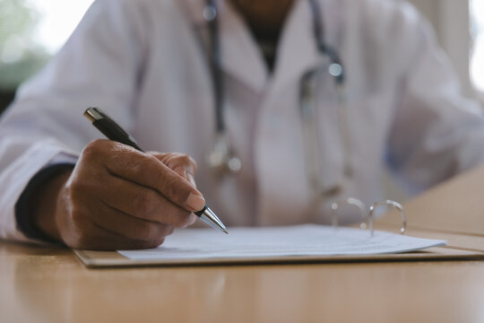 Doctor reviewing medical notes and patient records at a desk with stethoscope, representing healthcare documentation, clinical assessment, diagnosis, consultation and professional medical care.