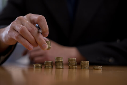 Hand stacking coins on a desk for financial planning and money management, representing savings, investment, budgeting, wealth growth, personal finance, income, profit and financial goals.