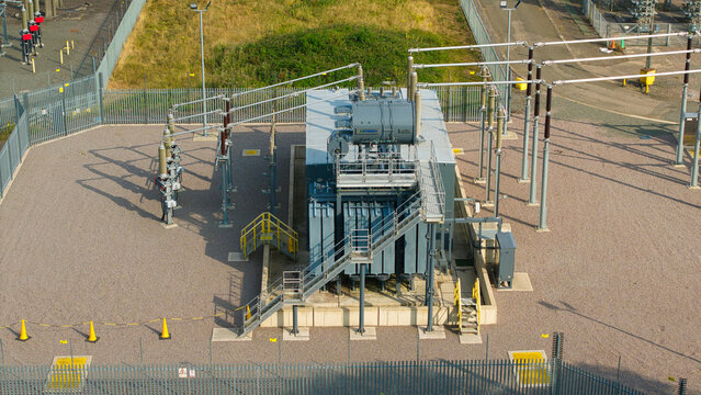 Aerial view of the Berkswell Substation featuring large electrical transformers, metal fencing, gravel ground, and industrial equipment in Coventry, England, United Kingdom.
