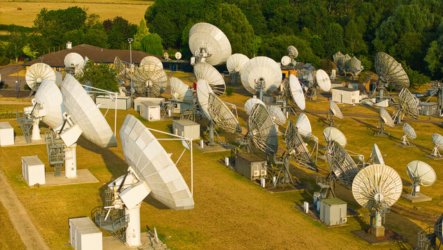 Aerial view of Satellite Mediaport Services Ltd. featuring numerous large satellite dishes and communication antennas arranged in a field in Long Lawford, England, United Kingdom.