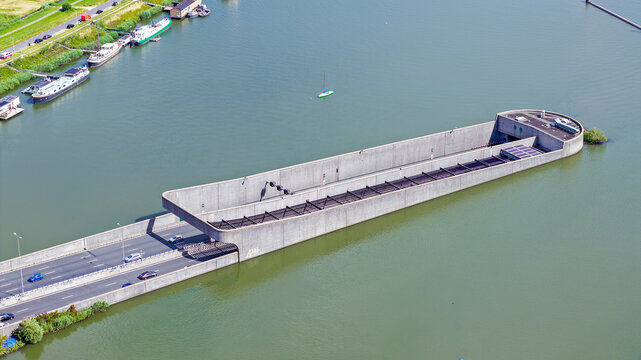 Aerial view of the Zeeburgertunnel entrance with cars driving into the tunnel, surrounded by the IJ river with boats in Amsterdam, Noord-Holland, Netherlands.