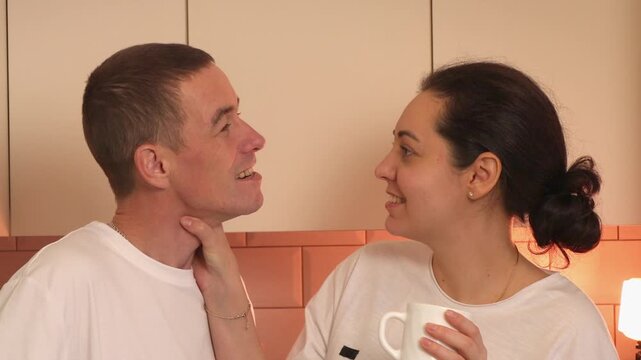 Portrait of young lovers enjoying a relaxed morning together in a comfortable kitchen. They exchange warm glances and meaningful conversation, highlighting trust, romance, and healthy communication.