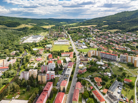 Aerial view of the Housing estate sidlisko 1. maja featuring residential apartment buildings, green spaces, and surrounding hills under a cloudy sky in Hnusta, Banska Bystrica Region, Slovakia.
