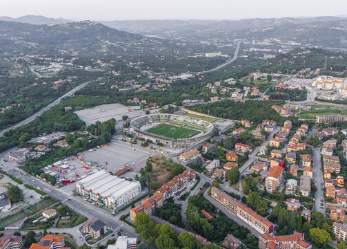 Aerial view of the Stadio Partenio-Adriano Lombardi stadium surrounded by residential buildings, roads, and lush green hills in Avellino, Campania, Italy.