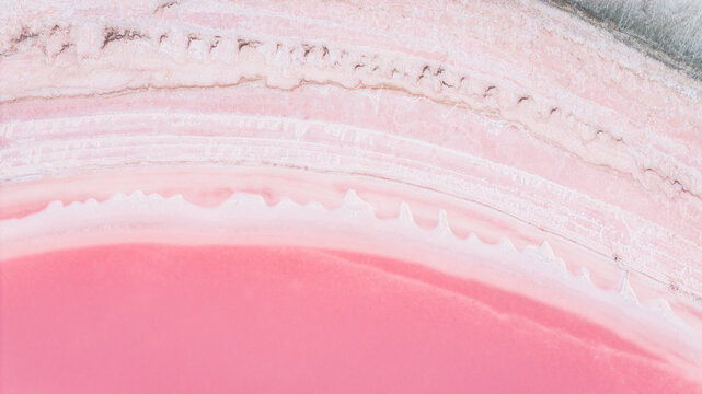 Aerial view of the pink salt pond shoreline in the Camargue region, featuring delicate mineral formations and vibrant saline water textures in France.