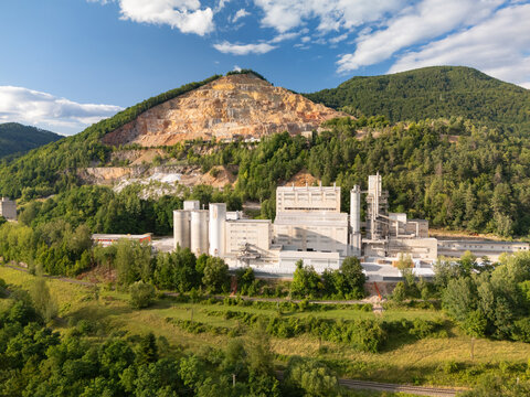 Aerial view of the CALMIT lime plant featuring industrial silos and processing facilities nestled against a forested hillside with a limestone quarry. Tisovec, Banska Bystrica Regio, Slovakia.