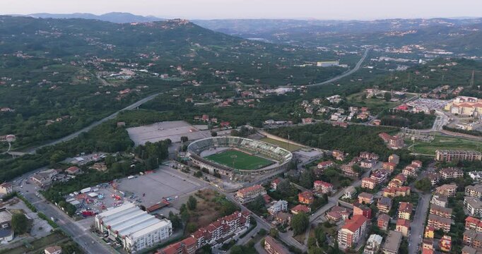 Aerial view of the Stadio Partenio-Adriano Lombardi surrounded by urban infrastructure, residential buildings, and rolling green hills in Avellino, Campania, Italy.