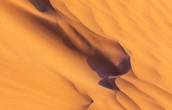 View of the golden sand dunes of the Sahara Desert with soft shadows and textures in Douz, Kebili Governorate, Tunisia.
