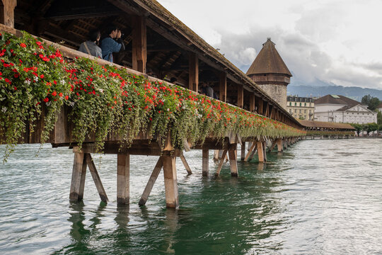 View of the historic Chapel Bridge adorned with vibrant flowers and the Wasserturm tower in Lucerne, Lucerne, Switzerland.